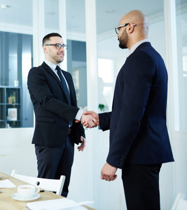 Business unity Handshaking men in suits standing by workplace