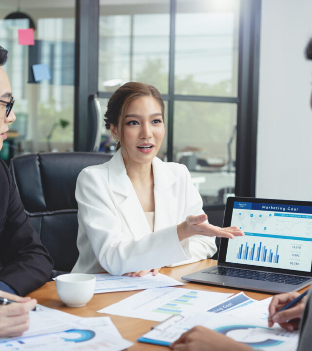 Group of Asian business people meeting about business plan and p Group of Asian business people meeting about business plan and present and explain stock financial chart from laptop computer at office.